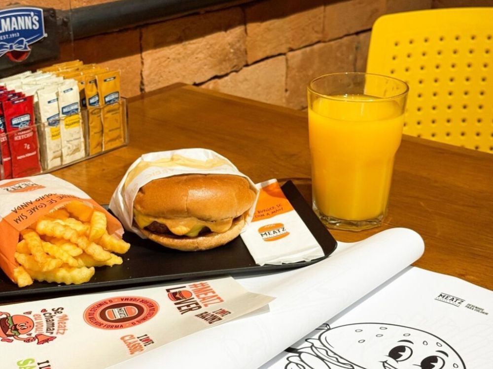 Combo com hambúrguer, batata frita e suco de laranja, simbolizando a popularização global e cultural na história do hambúrguer.