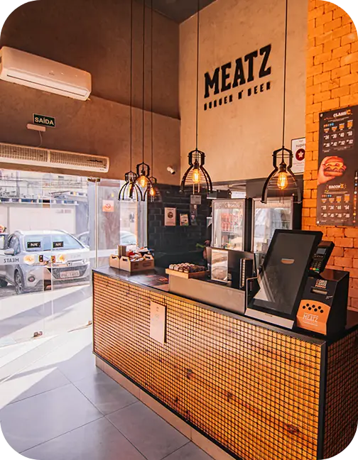 Interior da MEATZ com balcão, iluminação aconchegante e letreiro Burger & Beer